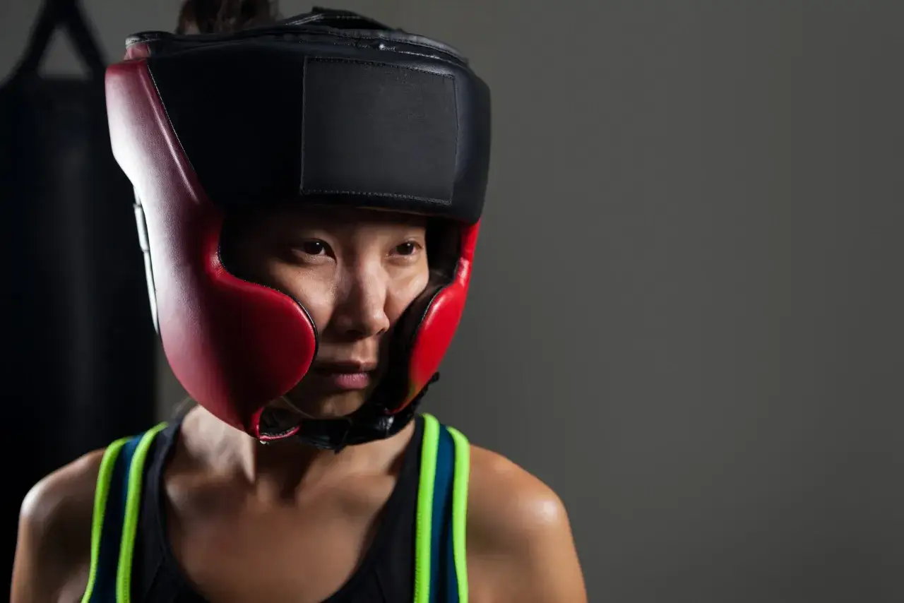 A boxer in a red and black headguard, ready for amateur vs professional boxing.