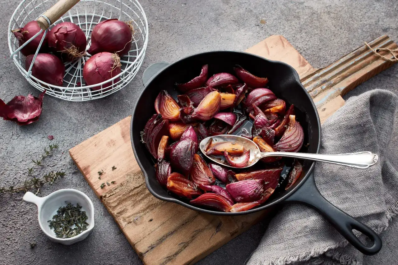 Rote Zwiebeln karamellisieren in einer Pfanne, verfeinert mit Kräutern und Balsamico. Köstliche Balsamico Zwiebeln, bereit zum Servieren.