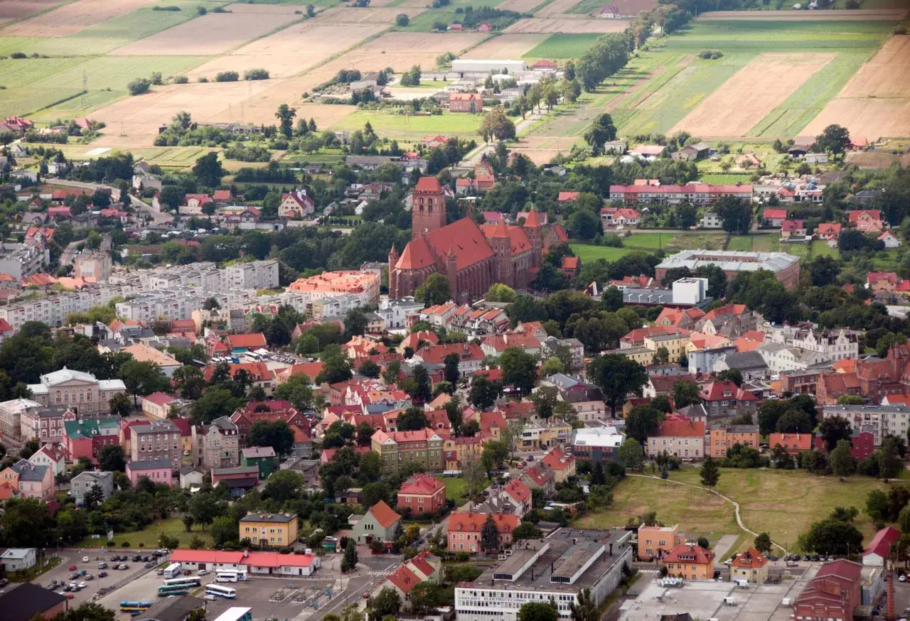 Widok z lotu ptaka na Kwidzyn, z dominującą katedrą i malowniczymi atrakcjami miasta otoczonymi polami.