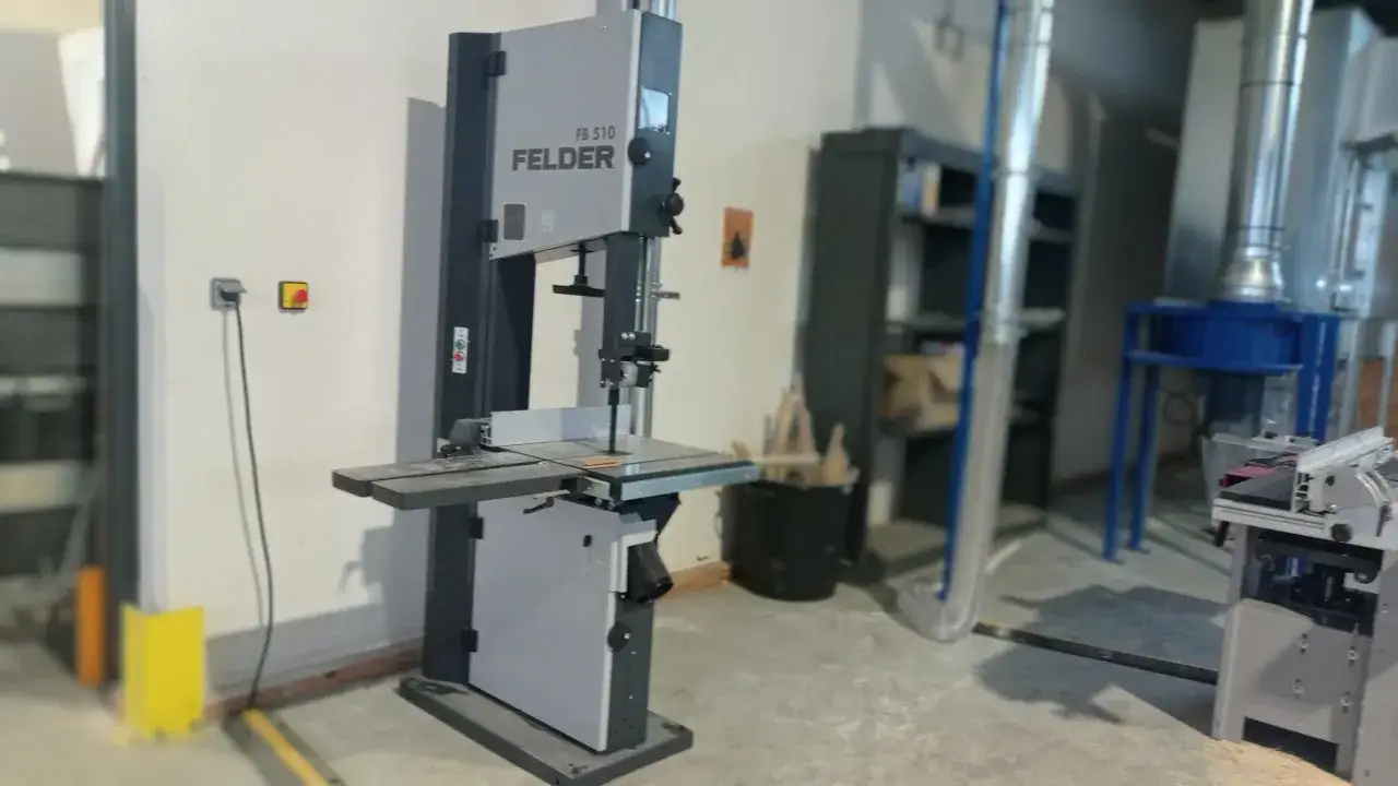 Une scie à ruban Felder FB 510, machine d'atelier essentielle pour la découpe précise du bois, se tient prête à l'emploi.