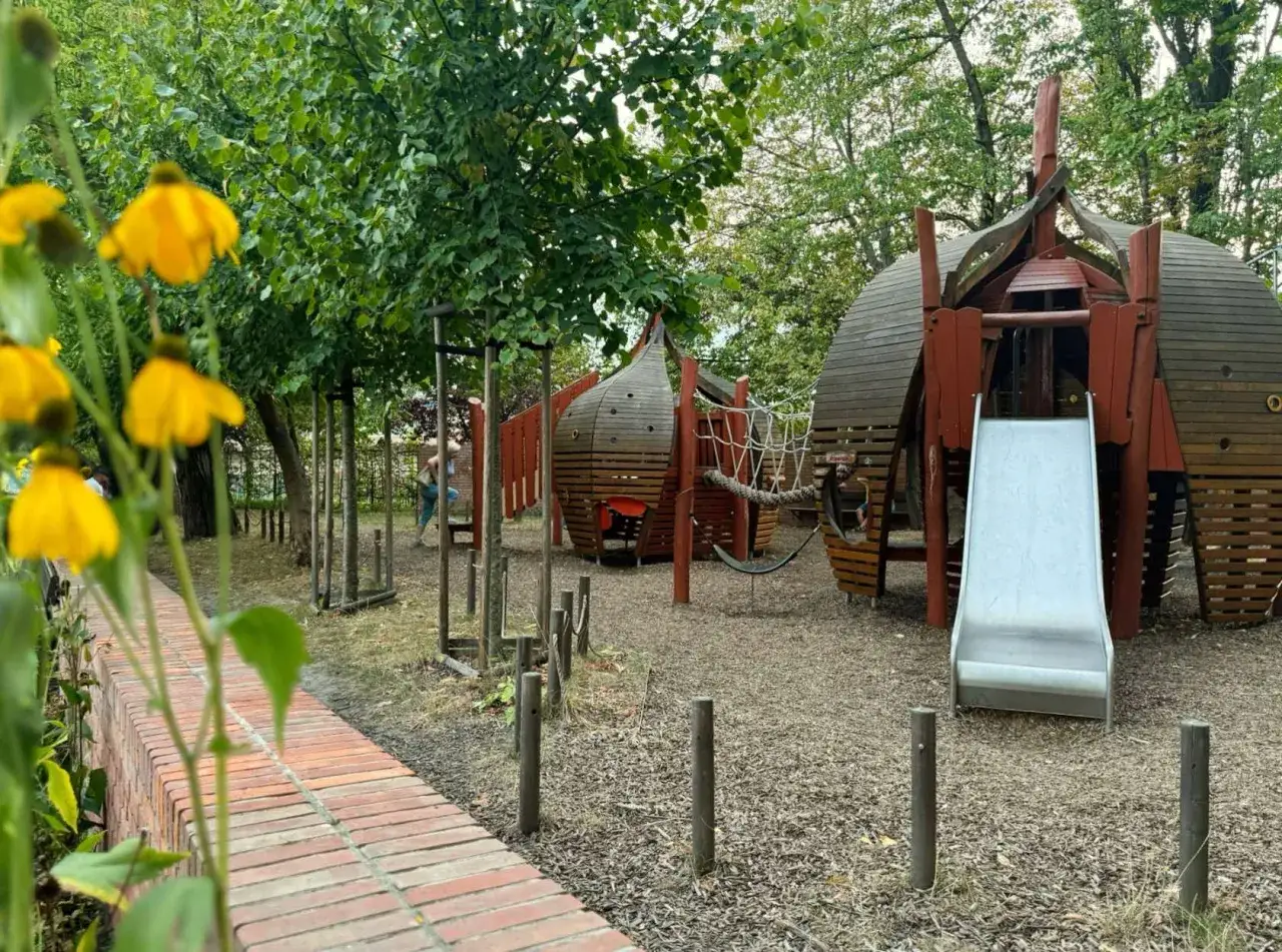 Drewniany plac zabaw w Krakowie zjeżdżalnią i domkami, idealny na wsp&oacute;lne chwile z dzieckiem.