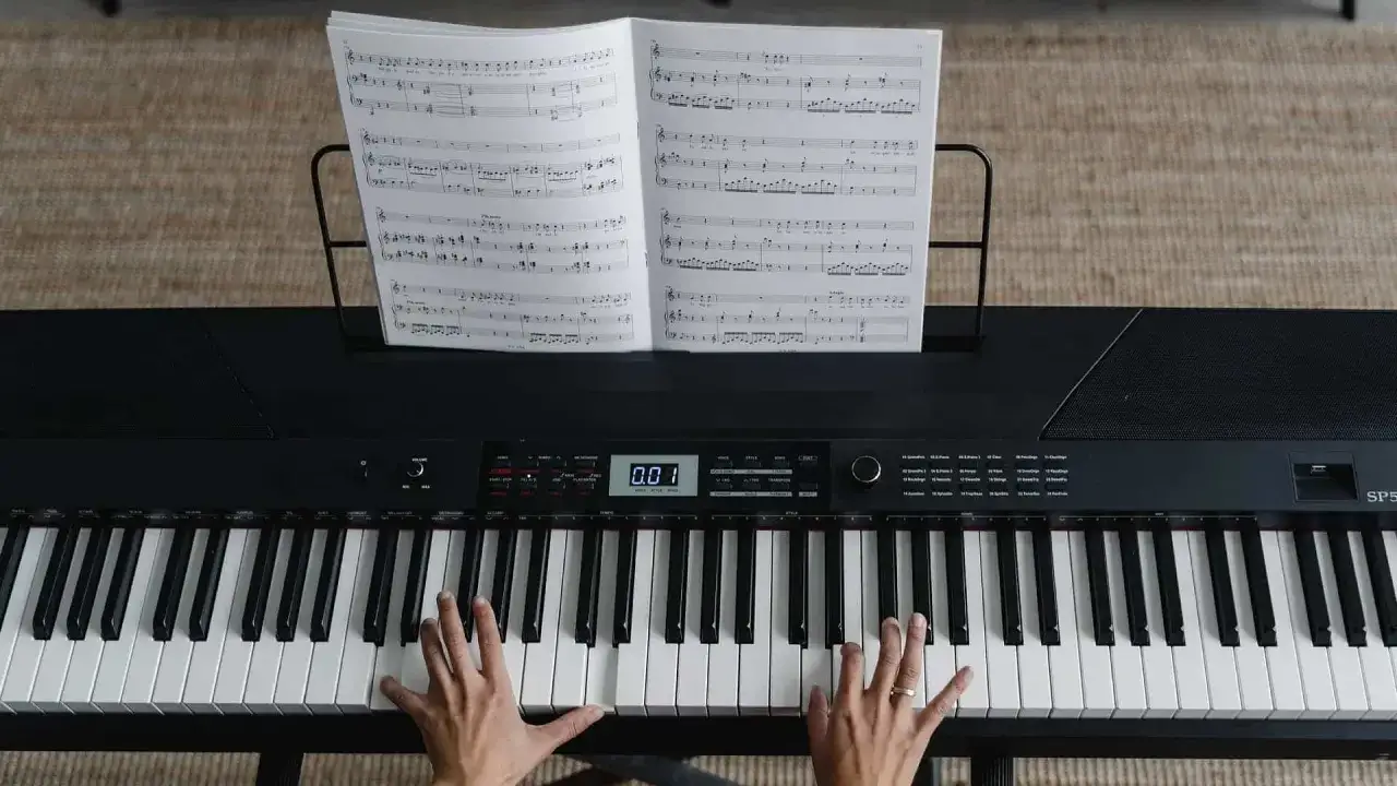Hände, die auf einer Tastatur spielen, Noten auf einem Notenständer.
