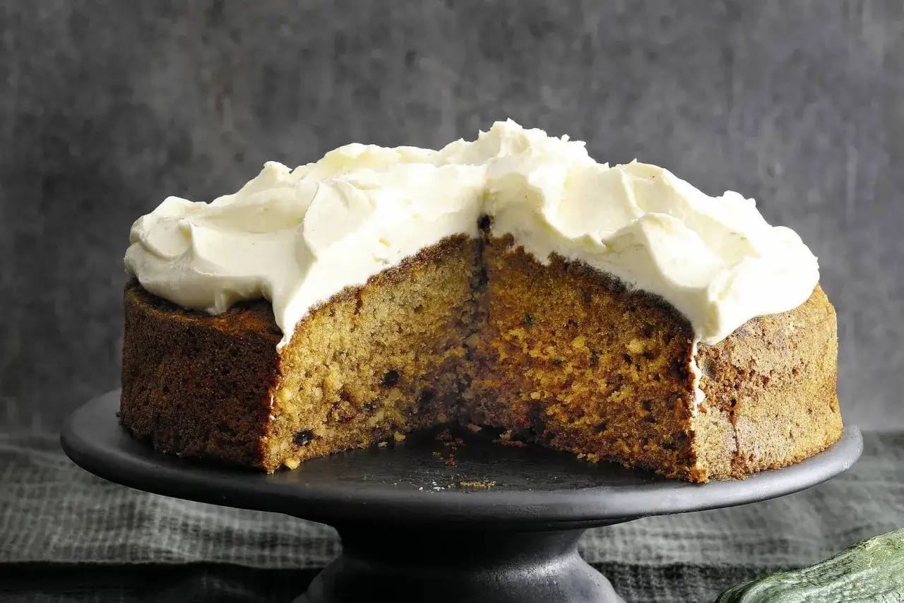 Saftiger Zucchini Kuchen mit cremigem Topping, auf einem schwarzen Tortenst&auml;nder.