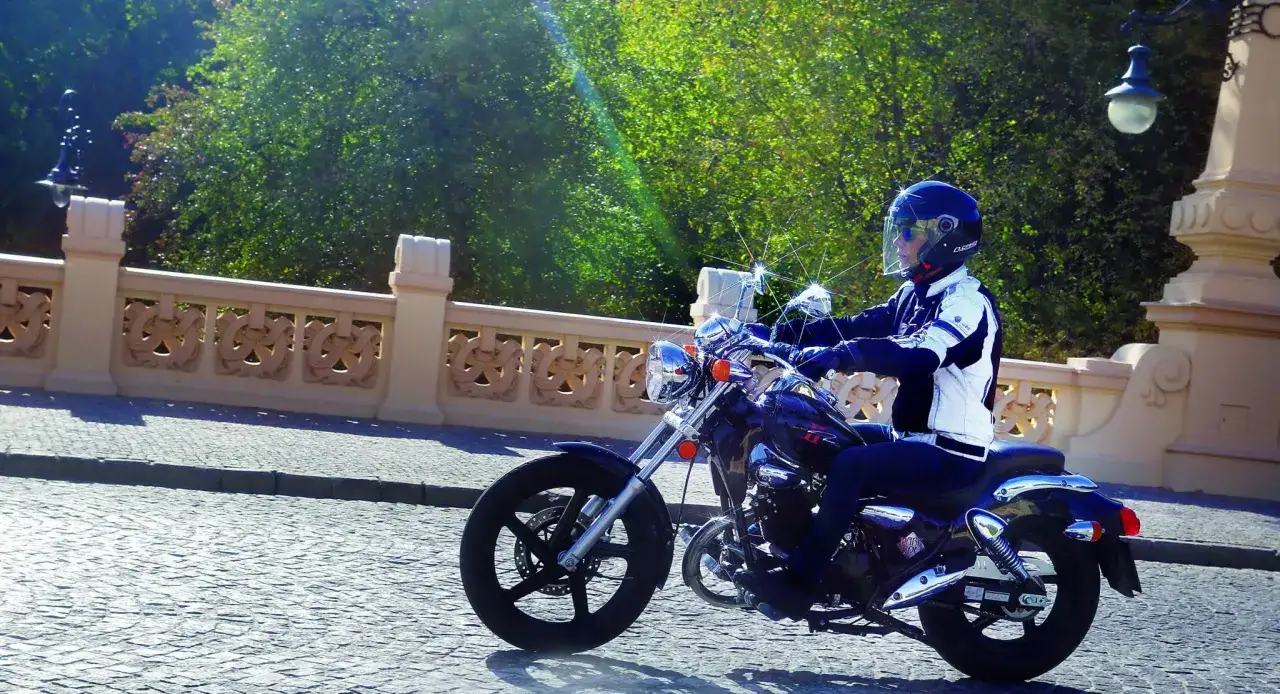 Motocyklista na Kymco Zing 125, zgrabnie pokonujący brukowaną ulicę. Dane techniczne tego modelu pozwalają na komfortową jazdę.