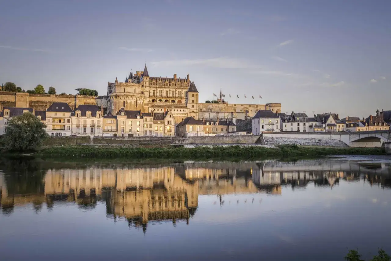 Le ch&acirc;teau d'Amboise se refl&egrave;te dans la Loire au coucher du soleil. Une belle image pour planifier la dur&eacute;e de votre visite au ch&acirc;teau d'Amboise.