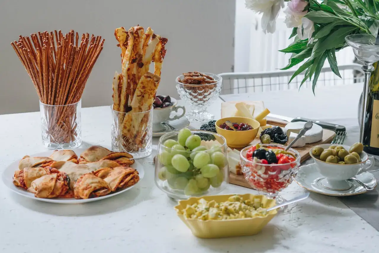 Kalter Snack-Buffet mit Grissini, Käse, Trauben, Oliven und gefüllten Teigtaschen – perfekt als kalte Snacks zum Vorbereiten am Vortag.
