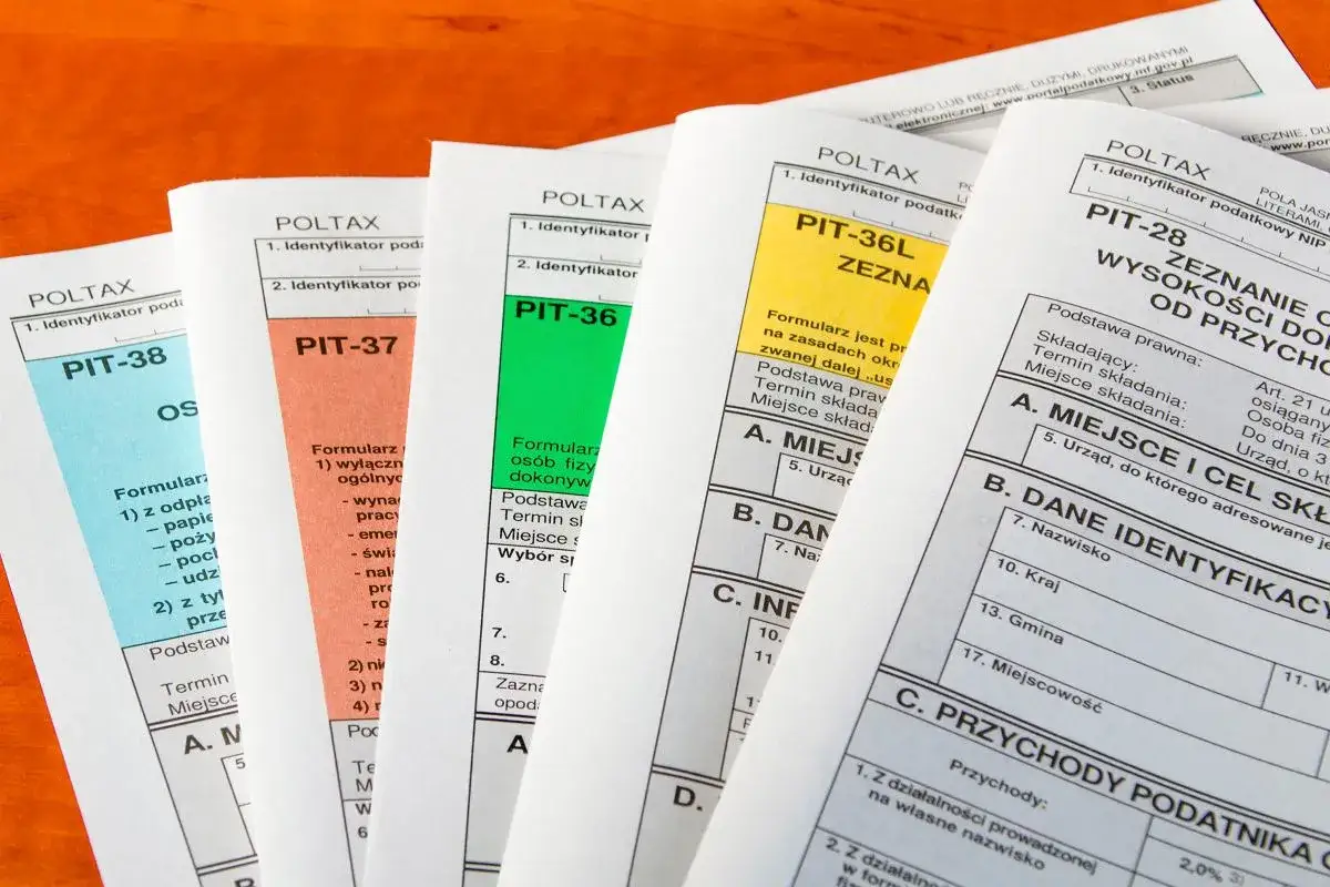 R&oacute;żne formularze PIT leżą obok siebie, sugerując rozliczenie podatkowe. Temat: upadłość konsumencka a rozliczenie PIT.