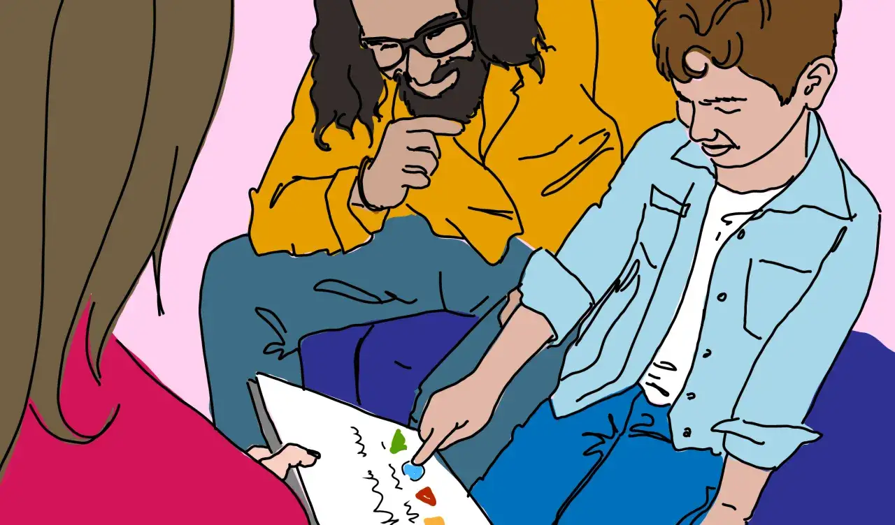 Barns autism utredning: en pojke pekar på en bild under samtal med en utredare och en vuxen.
