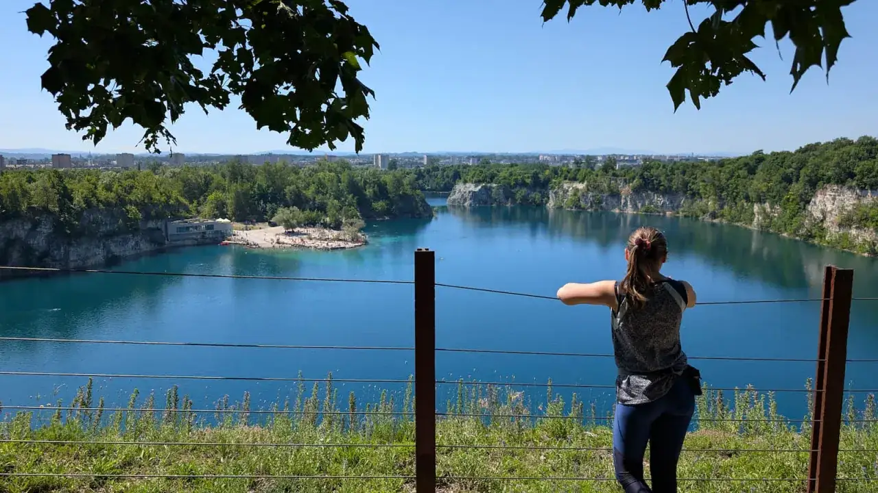 Widok na turkusową wodę i skaliste brzegi Zakrzówka w Krakowie. Kobieta wpatruje się w panoramę.
