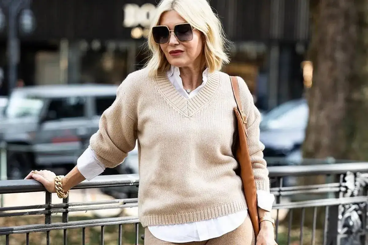 Elegancka kobieta po 50. w beżowym swetrze i białej koszuli. Stylowa moda dla pań po 50. z klasą.