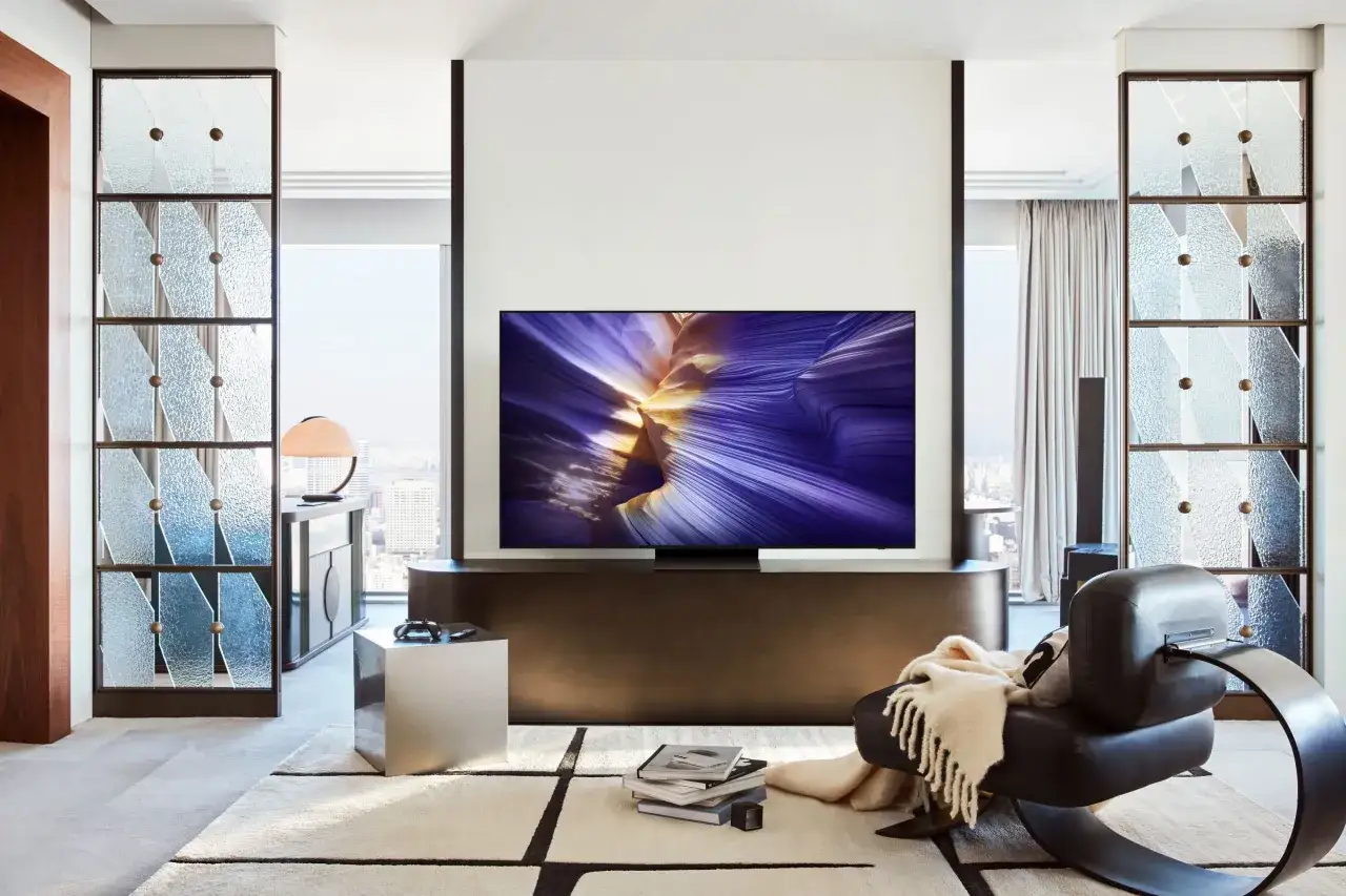 Nowoczesny salon z telewizorem Samsung S90D wyświetlającym zachwycający obraz. Wygodny fotel i stylowe dodatki tworzą przytulną atmosferę.
