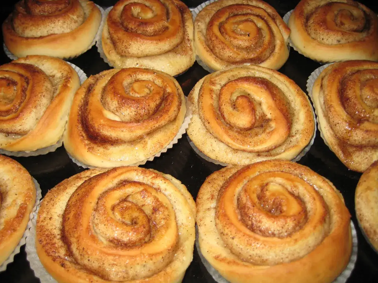 En n&auml;rbild av gyllene kanelbullar utan &auml;gg, perfekt bakade med en s&ouml;t kanelfyllning och str&ouml;socker.