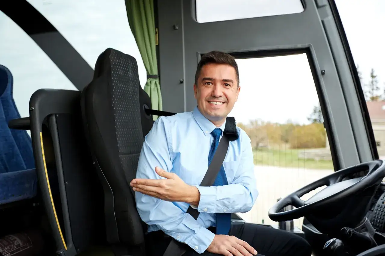 Conductor sonriente en su asiento, mostrando el interior del autobús. Su carnet d está listo para el viaje.