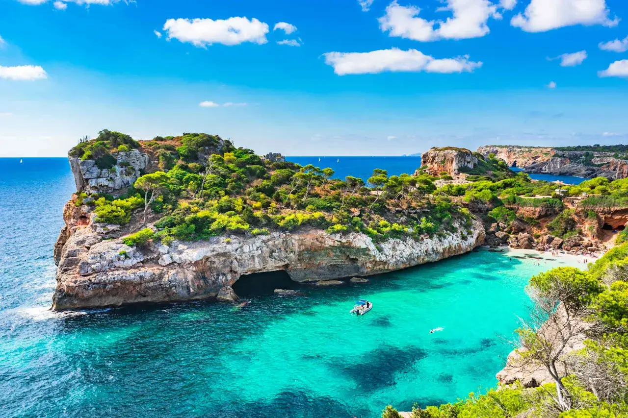 Baia con acque turchesi cristalline, scogliere verdi e una piccola spiaggia, tra le palma di maiorca spiagge pi&ugrave; belle.
