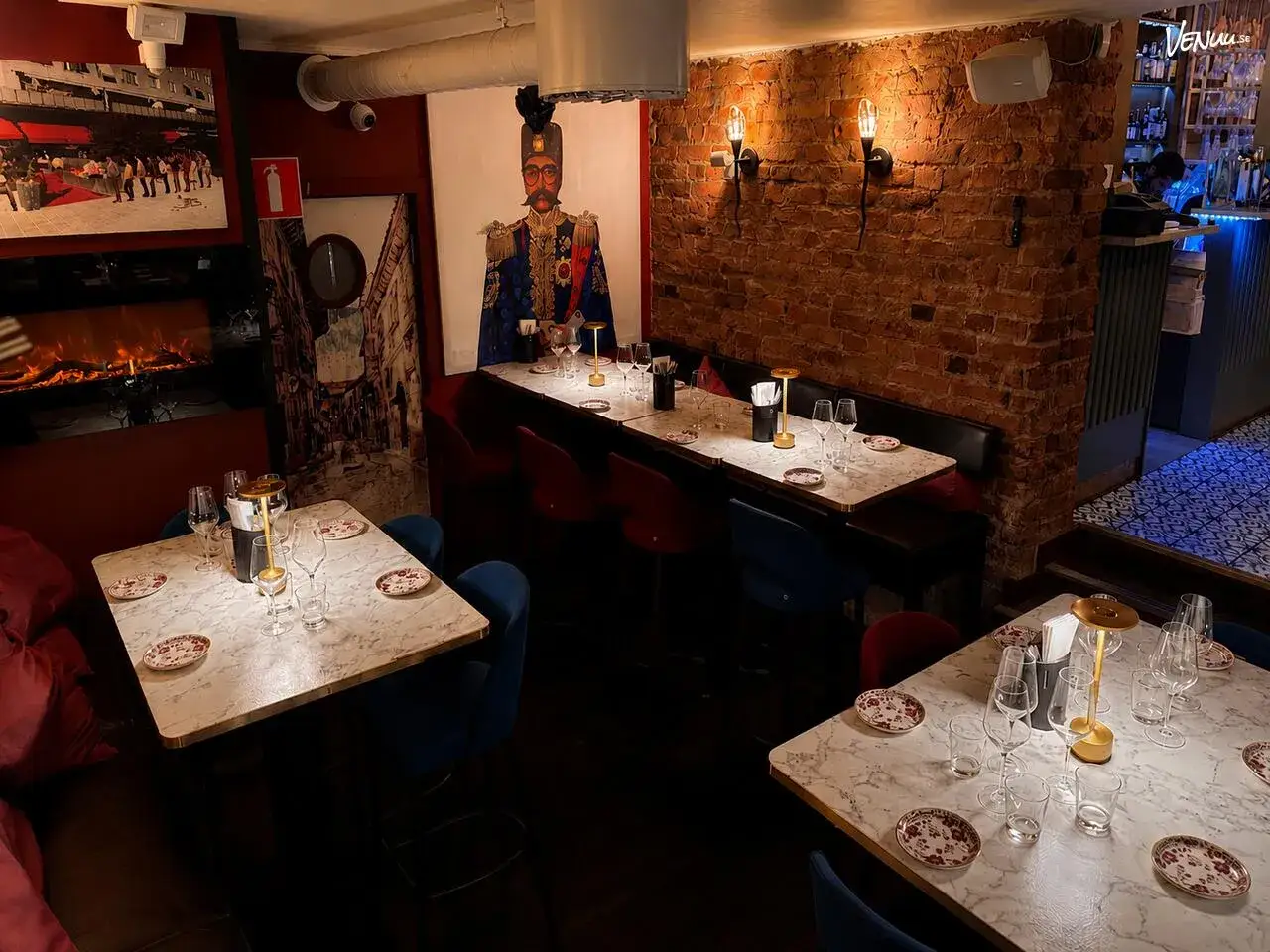 Mysig restaurang med tegelväggar, konst och dukade bord för tapas 28.
