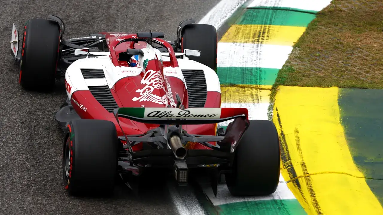Un coche Alfa Romeo F1 rojo y blanco toma una curva, con el logo de Alfa Romeo en el aler&oacute;n trasero.