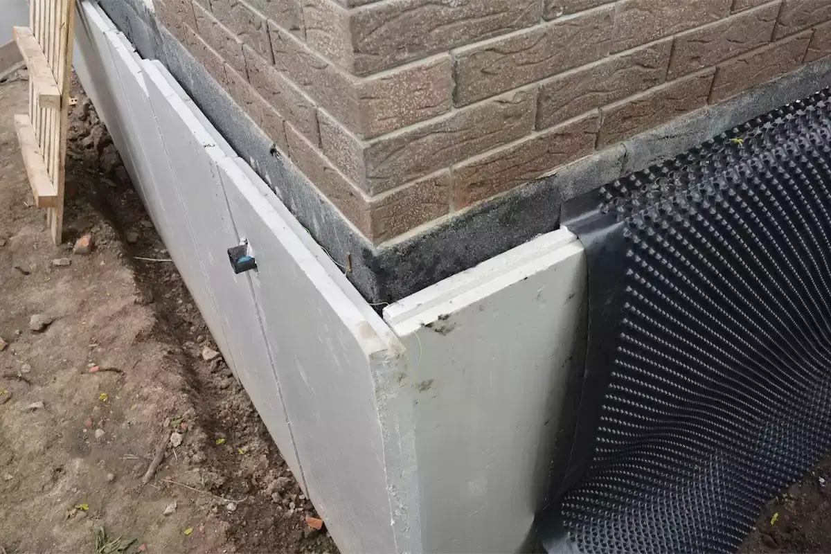 Styropian na fundamenty chroni ścianę przed wilgocią i zimnem. Widać też membranę kubełkową.