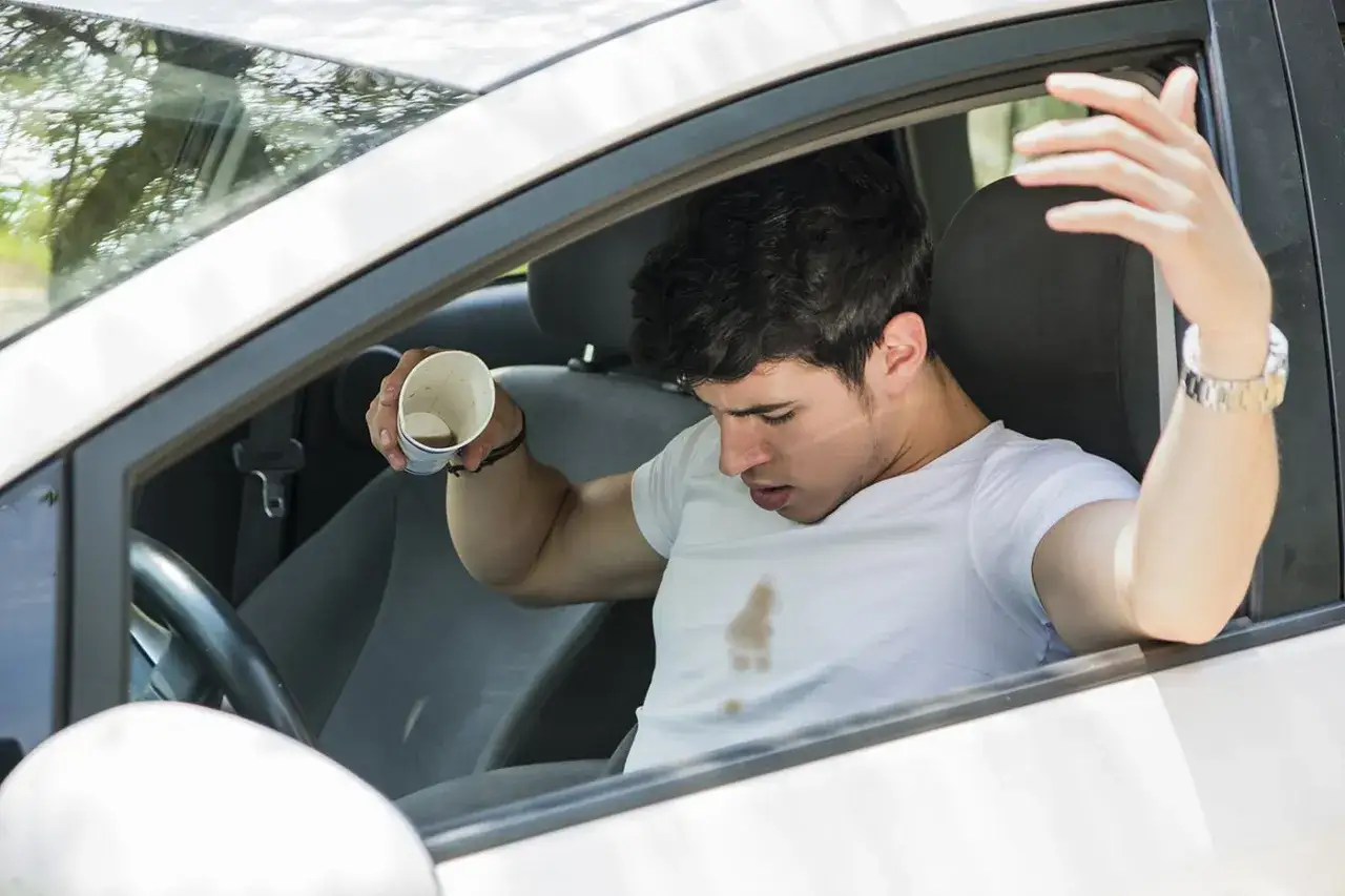 Hombre frustrado mira mancha en su camiseta, preguntándose como quitar manchas que no sabes de que son.