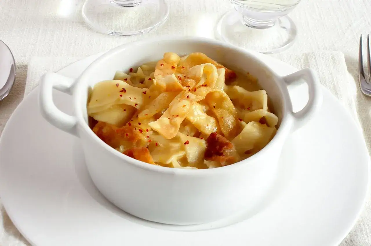 Un assaggio dei piatti tipici leccesi: pasta fresca con un sugo cremoso e un tocco di peperoncino, servita in una ciotola bianca.