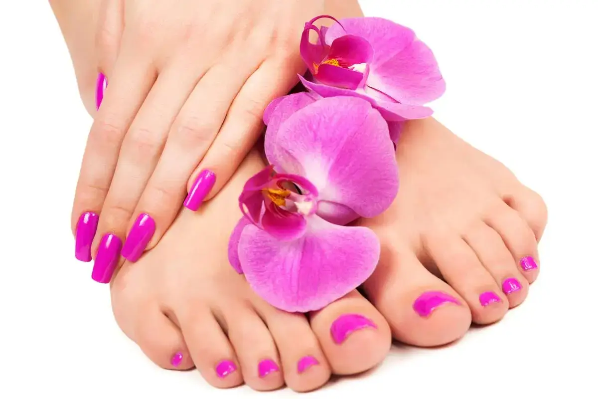 Mani e piedi curati con smalto fucsia brillante, decorati con orchidee rosa. Perfetti per sapere quanto dura il semipermanente.