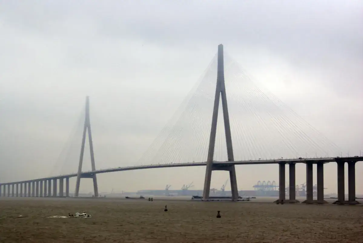 El puente Sutong se alza majestuoso sobre el agua, con sus pilares y cables creando un patrón impresionante contra el cielo nublado.