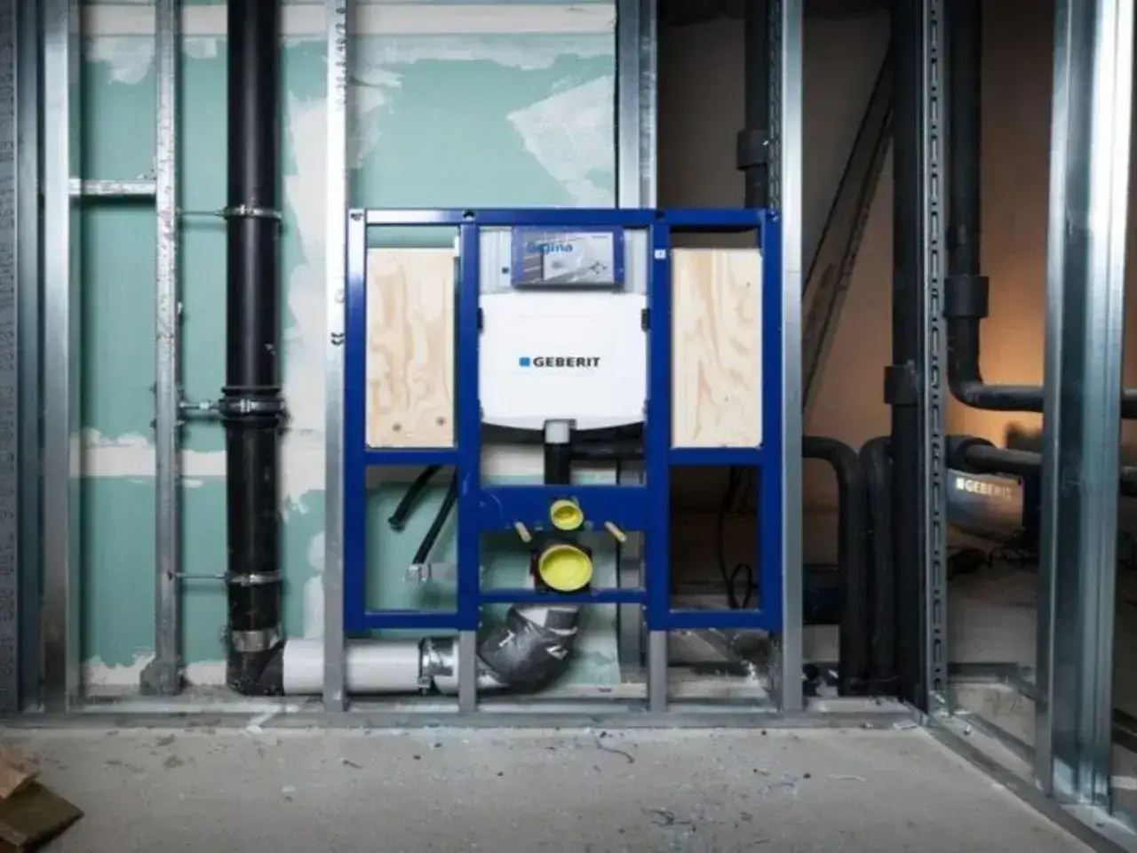 Montaż stelaża Geberit, widoczny podłączenie spłuczki do odpływu. Instalacja hydrauliczna w trakcie budowy.