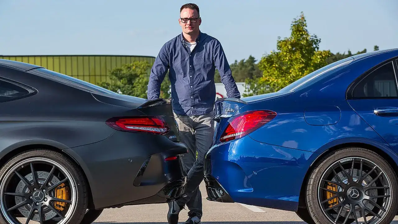 Hombre entre un coche azul y uno gris oscuro, mostrando la diferencia entre berlina y coupé.