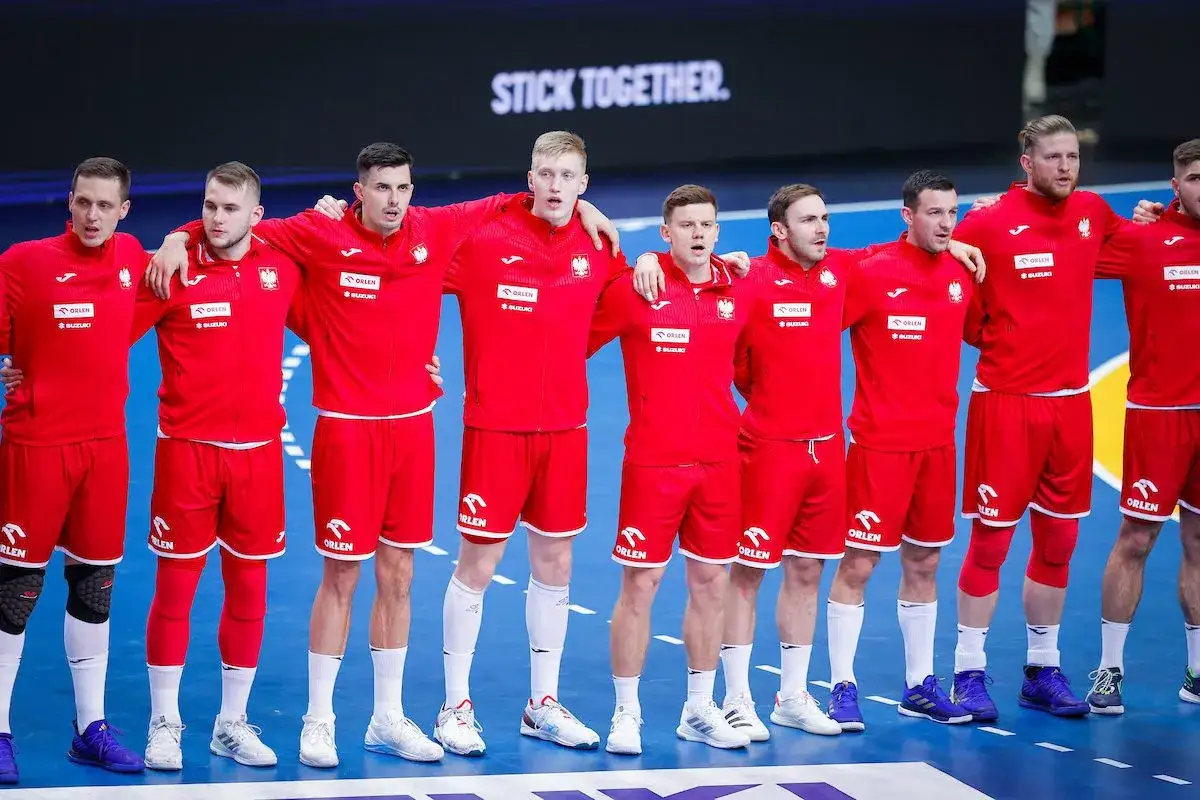 Drużyna me piłka ręczna w czerwonych strojach, z ramionami na barkach, gotowa do gry.