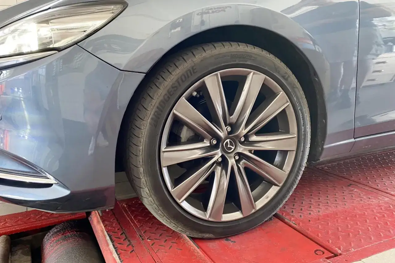 Szara Mazda na podnośniku, gotowa do diagnostyki. Sprawdź, jak sprawdzić amortyzatory, by jazda była bezpieczna.
