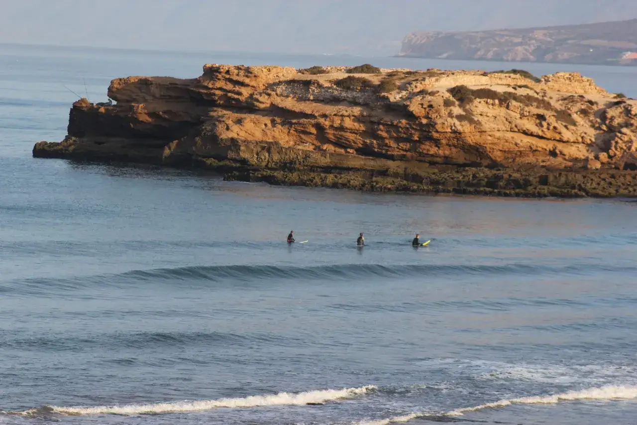 Trois surfeurs attendent la vague parfaite pr&egrave;s des falaises de Tamraght.