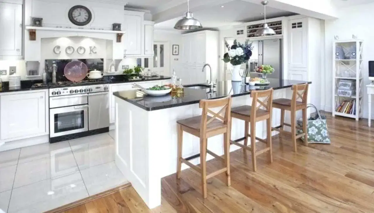 Îlot de cuisine moderne avec tabourets, délimitant le sol de la cuisine et du salon.