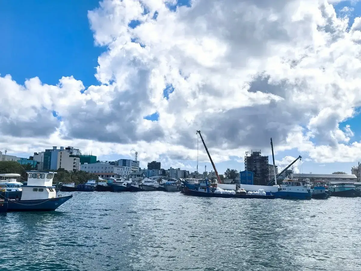 Port w stolicy Malediwów, Malé, z licznymi łodziami i budynkami w tle.