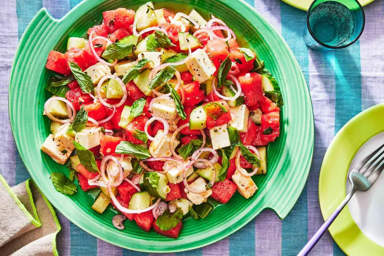 Erfrischender Wassermelonen Salat mit Feta, Gurke und Minze auf einem grünen Teller. Perfekt für heiße Tage!
