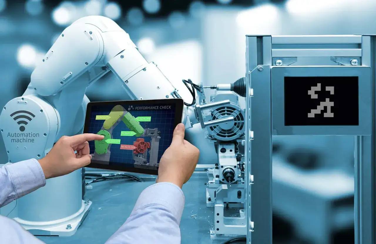Ramię robota i tablet z danymi o wydajności części. To przyszłość przemysłowego internetu rzeczy, gdzie maszyny komunikują się i optymalizują pracę.