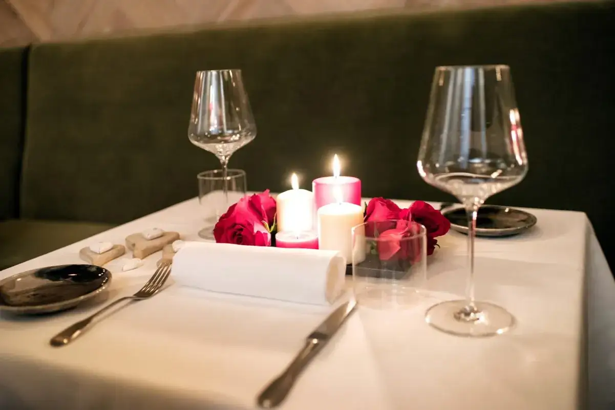 Dressage de table de restaurant romantique avec bougies, roses et verres à vin.
