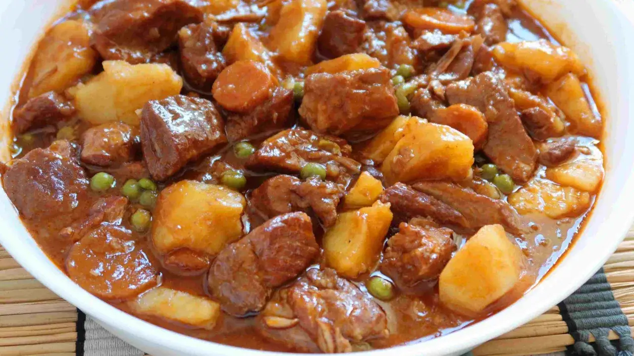 Un reconfortante estofado de cerdo con trozos tiernos de carne, patatas doradas y guisantes verdes en una rica salsa.