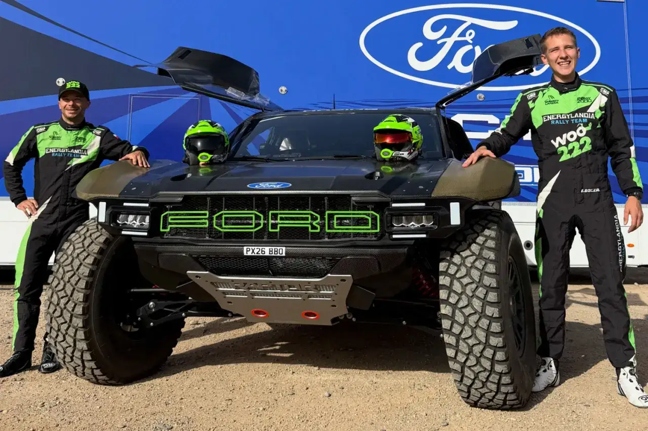 Dwóch kierowców w kombinezonach zespołu Energylandia Rally Team pozuje obok potężnego Forda.