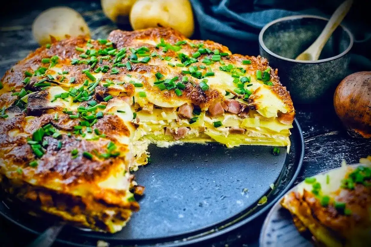 Herzhafte Kartoffel-Schinken-Gratin-Schichten, ein k&ouml;stliches Rezept mit Kartoffeln als Hauptspeise, bestreut mit frischem Schnittlauch.