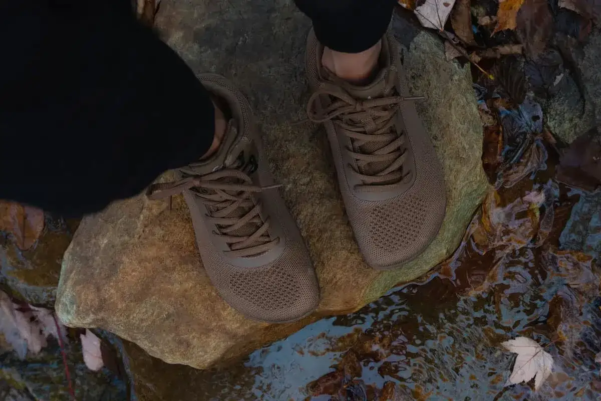 Brown mesh boots on rocks near water. Wondering should you size up in boots? These look true to size for a comfortable hike.