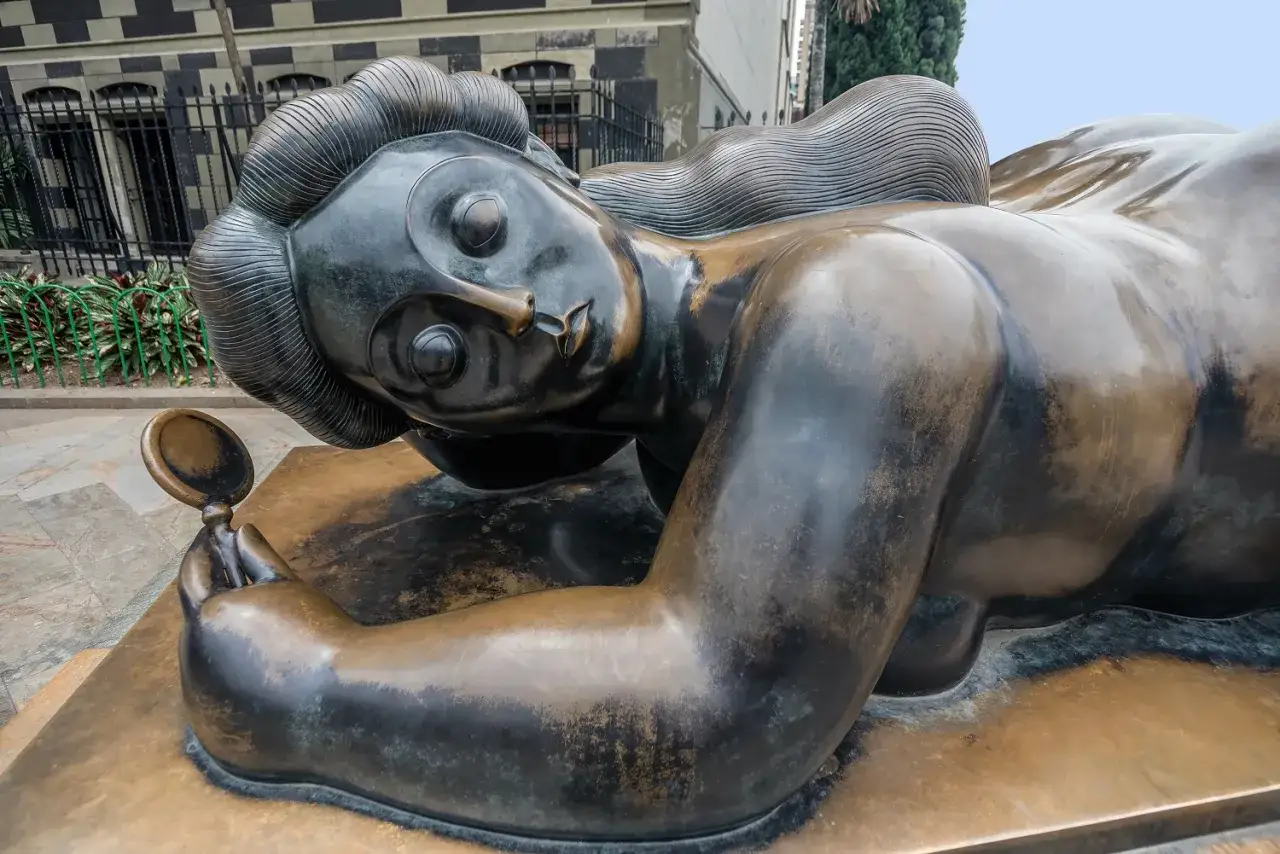 Sculpture d'une femme allongée tenant un miroir, œuvre d'un sculpteur français.
