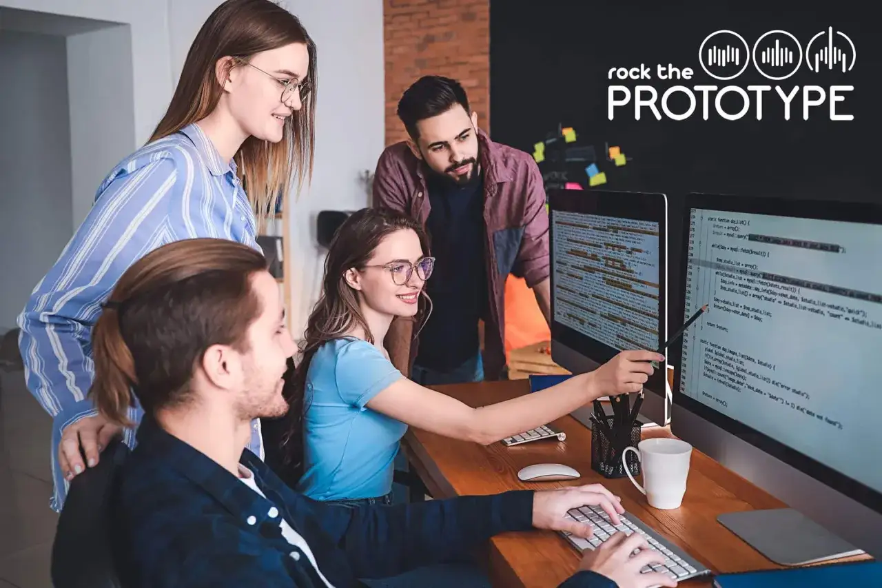 Vier Personen arbeiten im Mob Programming an einem Prototypen. Sie blicken auf zwei Bildschirme mit Code.
