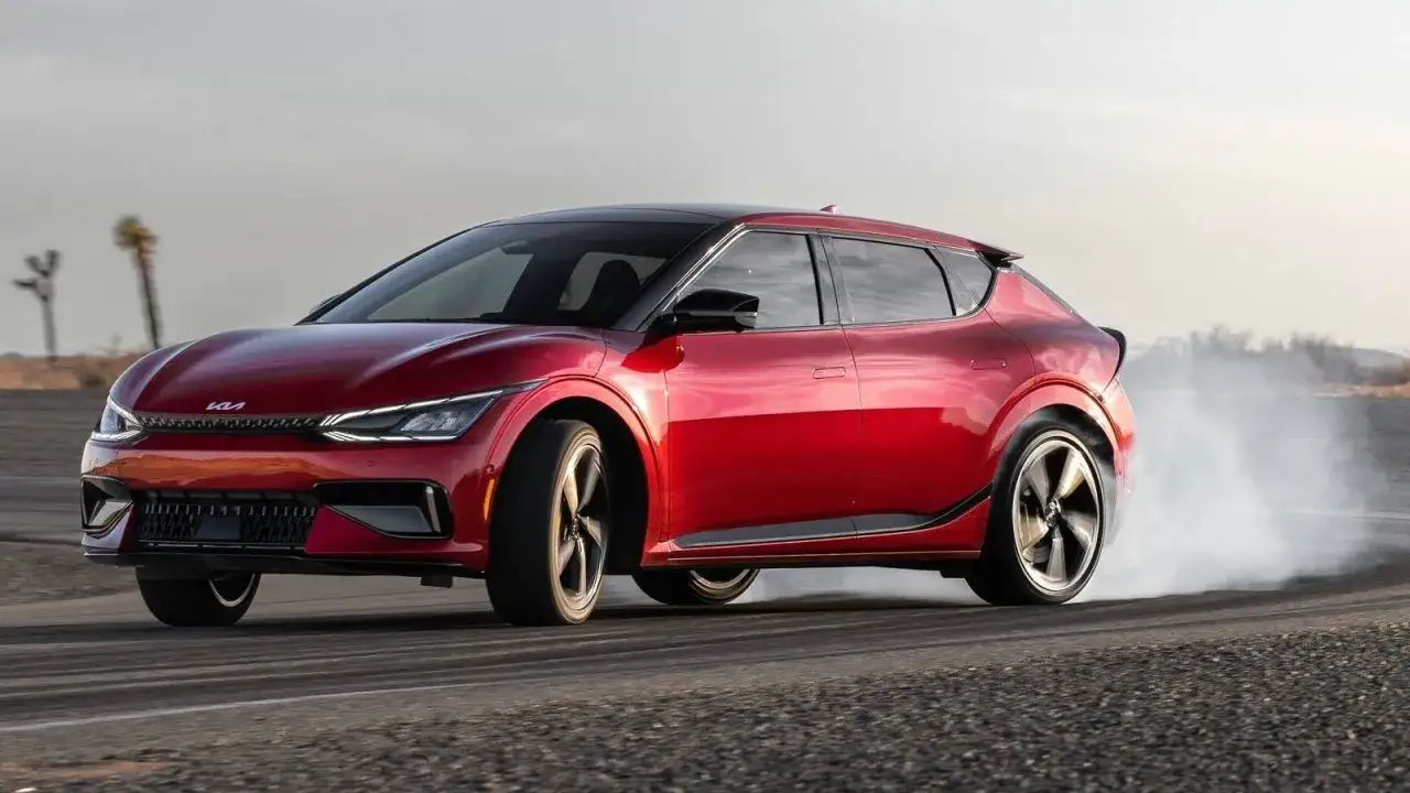 Czerwone Kia EV6 GT w poślizgu, z opon dymiących na pustynnej drodze.