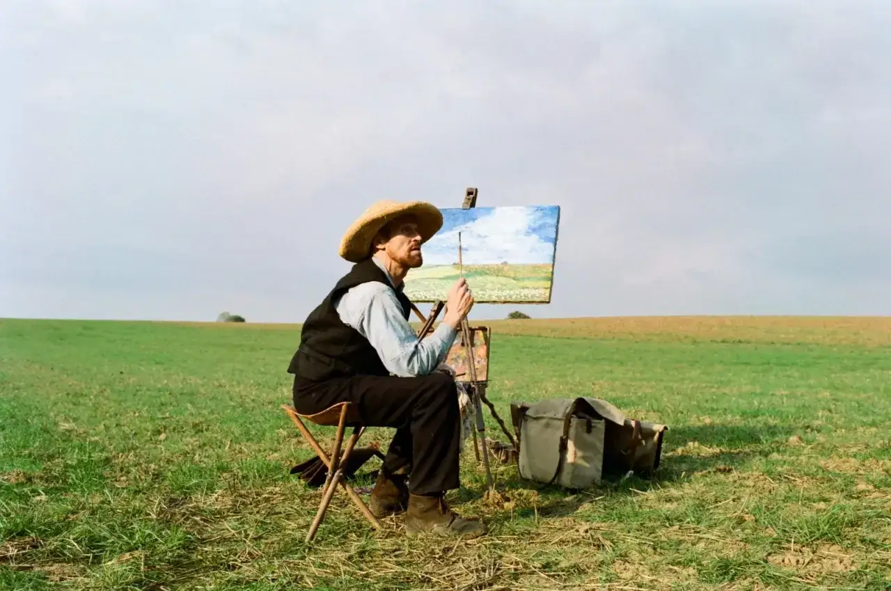 Van Gogh u bram wieczności, maluje krajobraz pola pod błękitnym niebem.