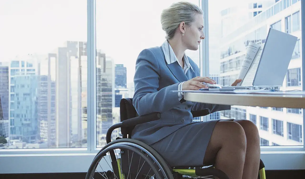 Donna in carrozzina lavora al computer, un esempio di come l'invalidità civile non sia un ostacolo al lavoro part time.