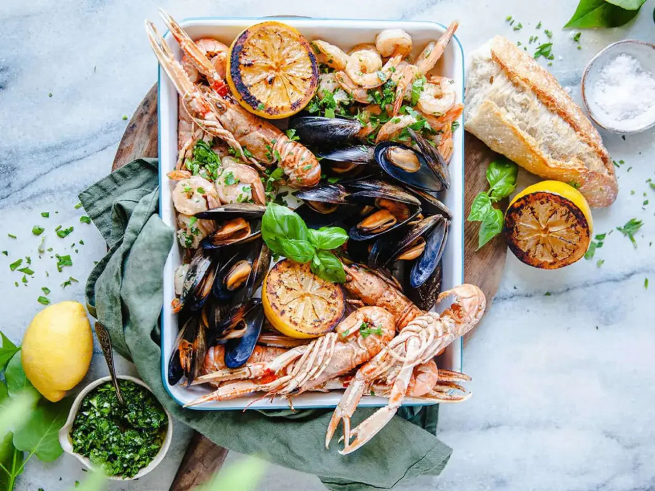 En stor bricka med frutti di mare, inklusive r&auml;kor, musslor och havskr&auml;ftor, serveras med grillad citron, br&ouml;d och &ouml;rts&aring;s.