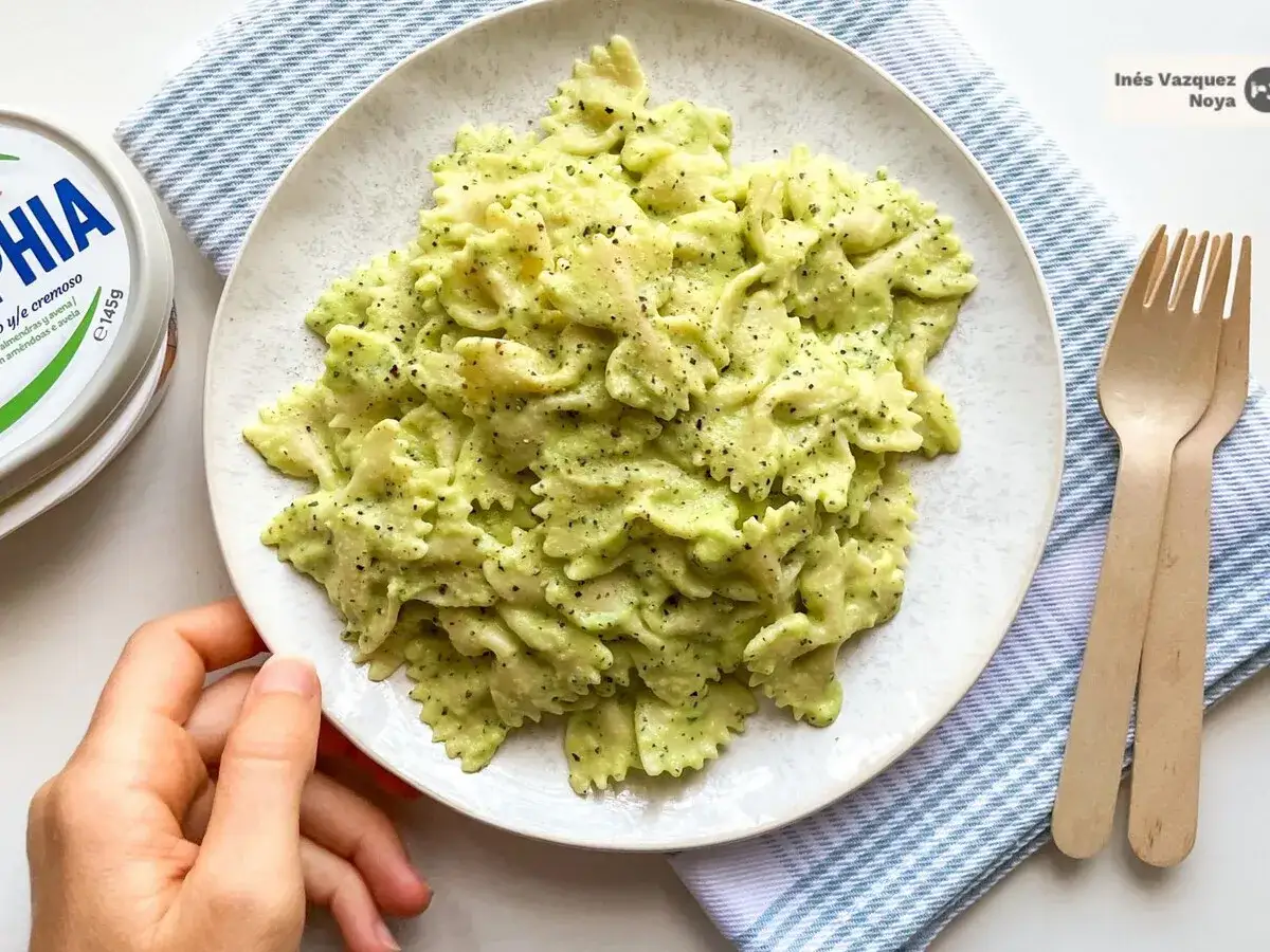 Pasta con calabacín cremosa, servida en un plato blanco con tenedores de madera.