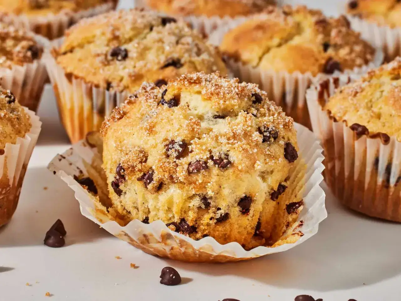 En närbild på nybakade muffins med chokladbitar, toppade med socker. Perfekt för fikat!
