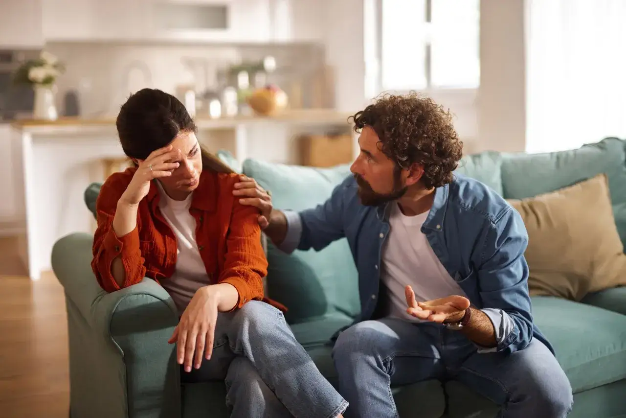 Uomo con mano sulla spalla di donna, che sembra volerla far sentire in colpa. Lei &egrave; visibilmente turbata.