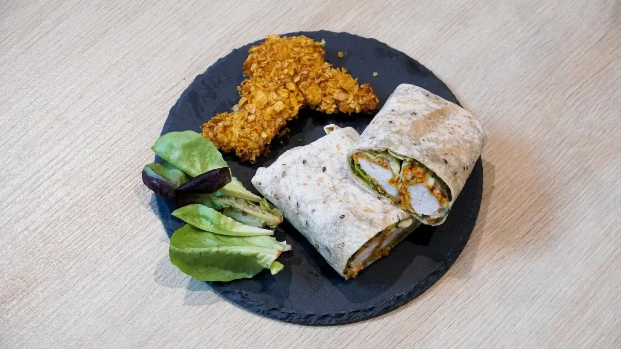 Pyszny kebab w tortilli, idealnie zawinięty, z chrupiącymi kawałkami kurczaka i świeżą sałatką.
