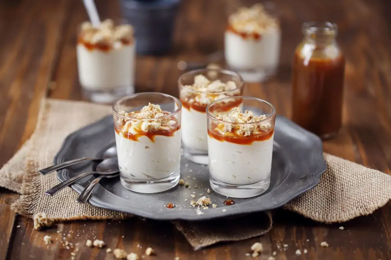 Trois verrines de mousse vanille onctueuse, nappées de caramel et garnies de miettes croustillantes. Un délice à savourer.